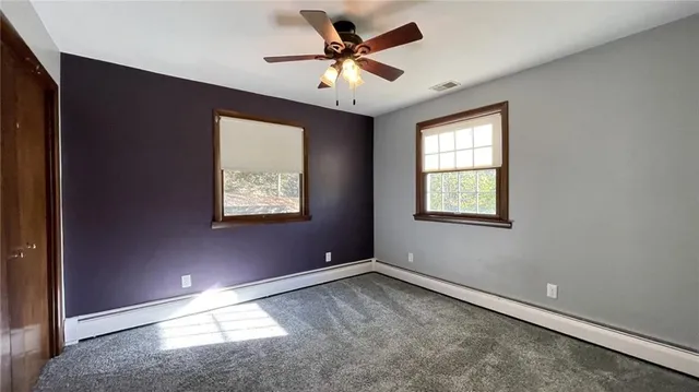 an empty room with windows and fan