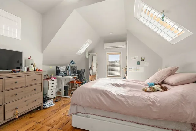 a bedroom with a bed a flat tv screen and dresser