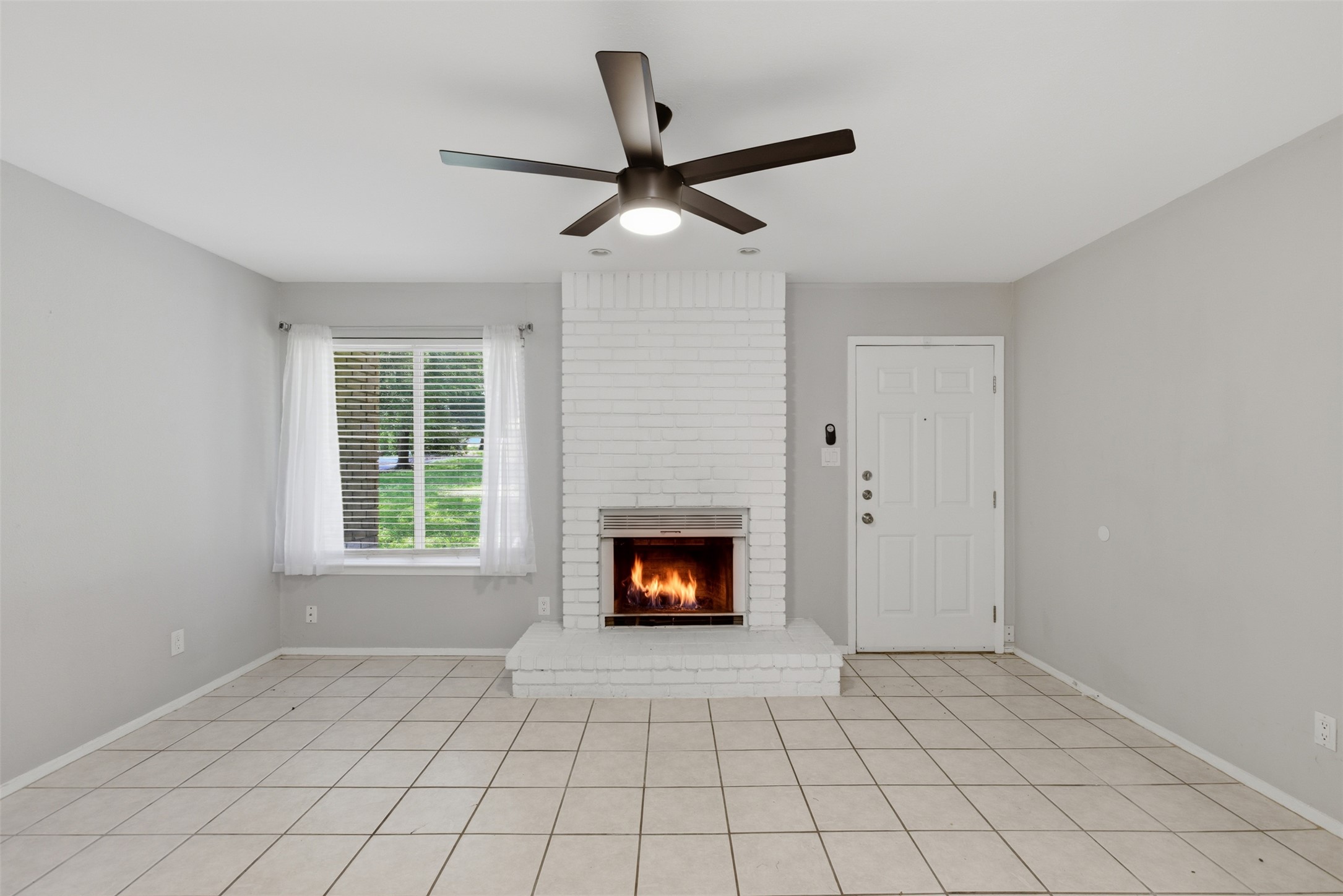 4204 Hudson Bend Road, Unit B Austin, TX 78734 - Photo 8 of 37 Living area featuring a white brick fireplace with hearth, tile flooring, a window with horizontal blinds, and a ceiling fan with integrated lighting