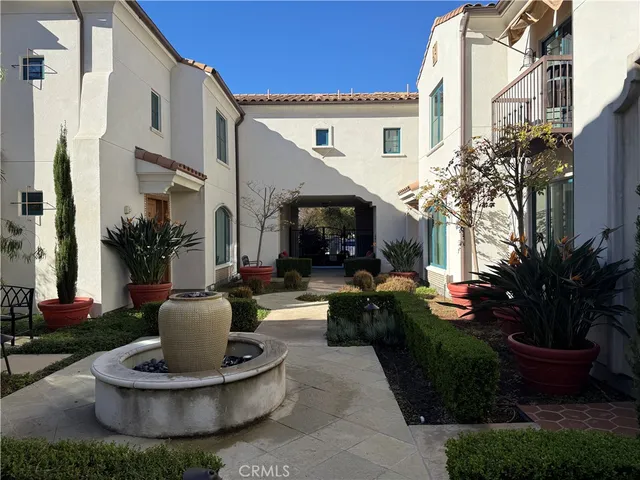 a view of a house with potted plants and a fountain