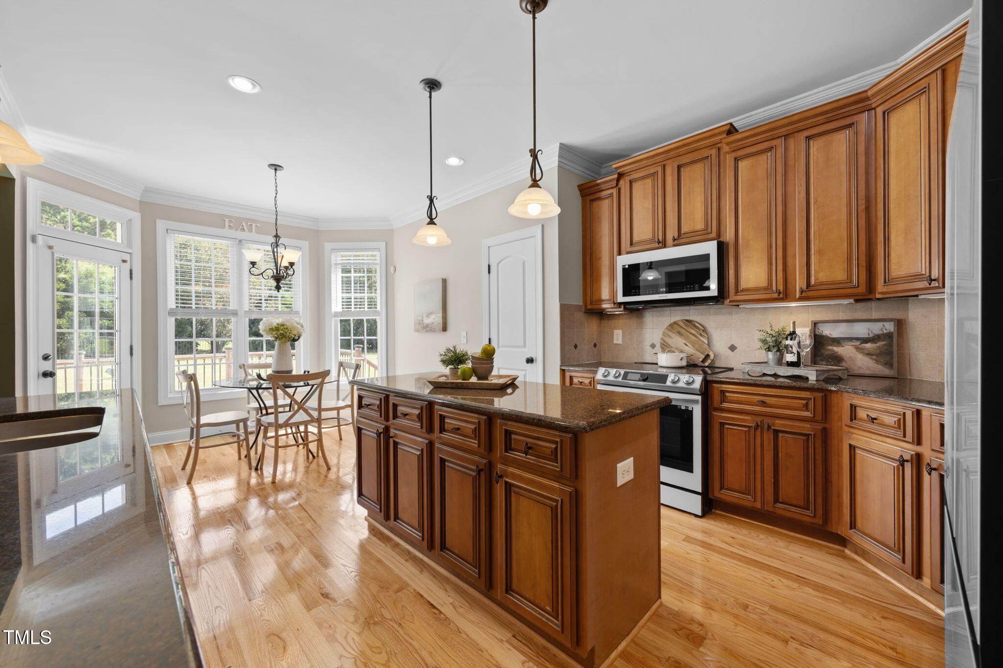 6313 Southern Charm Lane Raleigh, NC 27603 - Photo 3 of 38 a kitchen with stainless steel appliances granite countertop a stove top oven a sink dishwasher a dining table and chairs with wooden floor