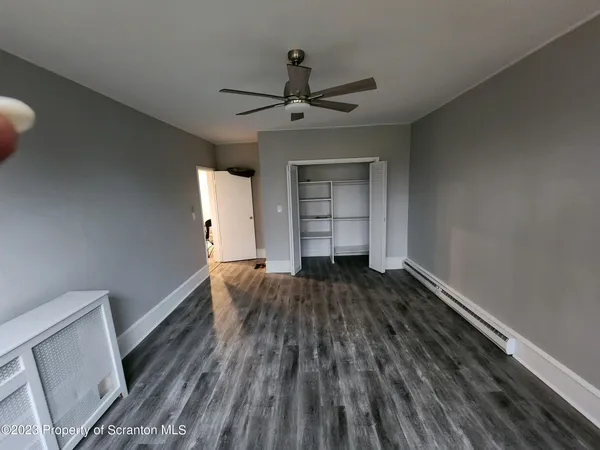 a view of empty room with wooden floor and fan