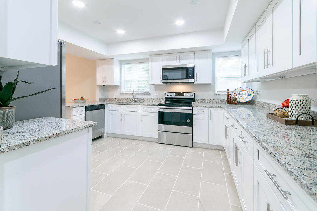 a large kitchen with stainless steel appliances granite countertop a stove sink and cabinets