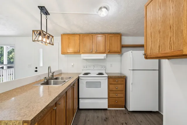 a kitchen with a sink a stove cabinets and a wooden floor
