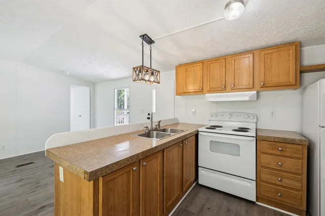 a kitchen with a sink a stove cabinets and a wooden floor