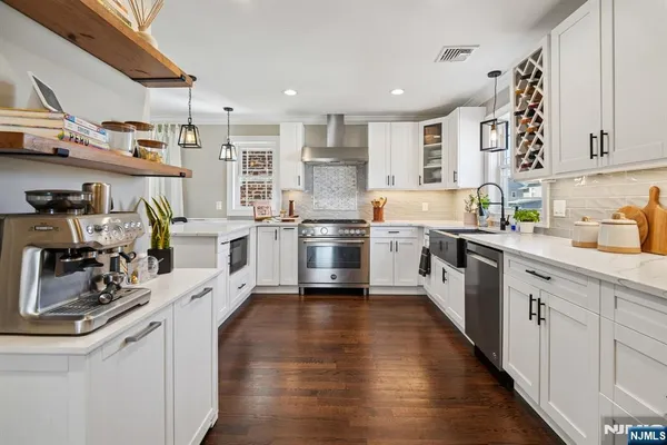 a kitchen with stainless steel appliances a sink a stove top oven a wooden floor and cabinets