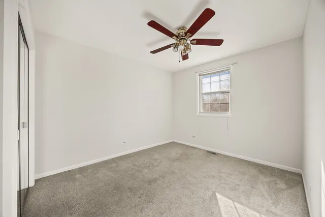 an empty room with window and ceiling fan