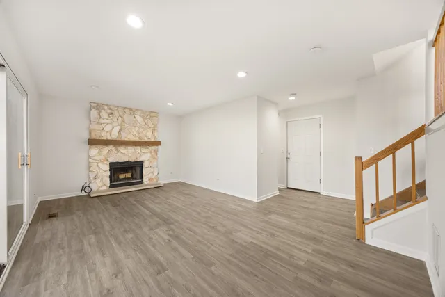 a view of an empty room with wooden floor fireplace and a window
