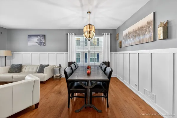 a view of a dining room and livingroom with furniture wooden floor a chandelier