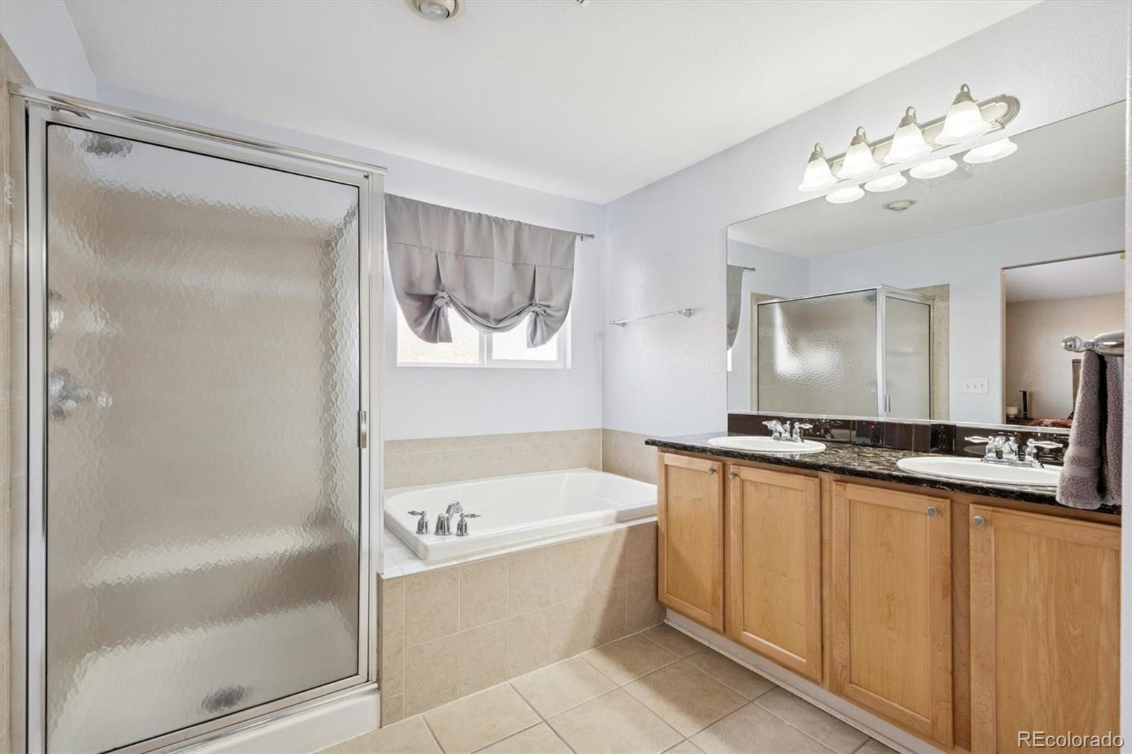 3431 Grove Street Brighton, CO 80601 - Photo 22 of 34 a bathroom with a tub a mirror and a shower