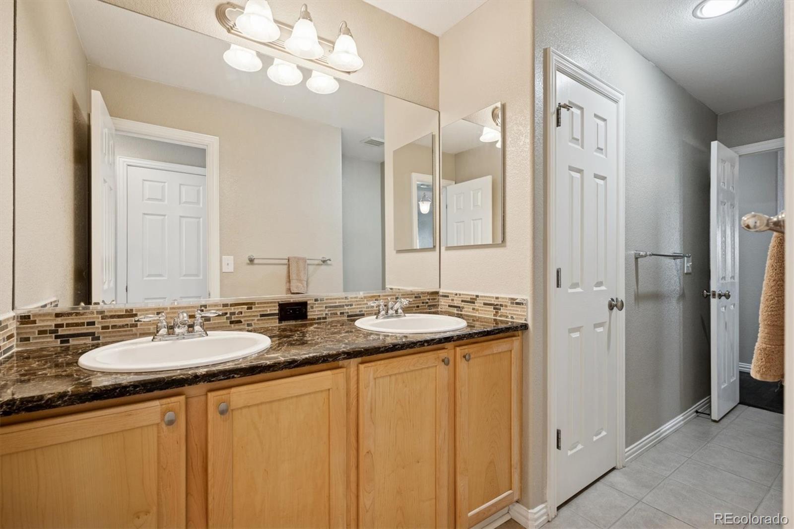 3431 Grove Street Brighton, CO 80601 - Photo 23 of 34 a bathroom with a granite countertop sink and a mirror