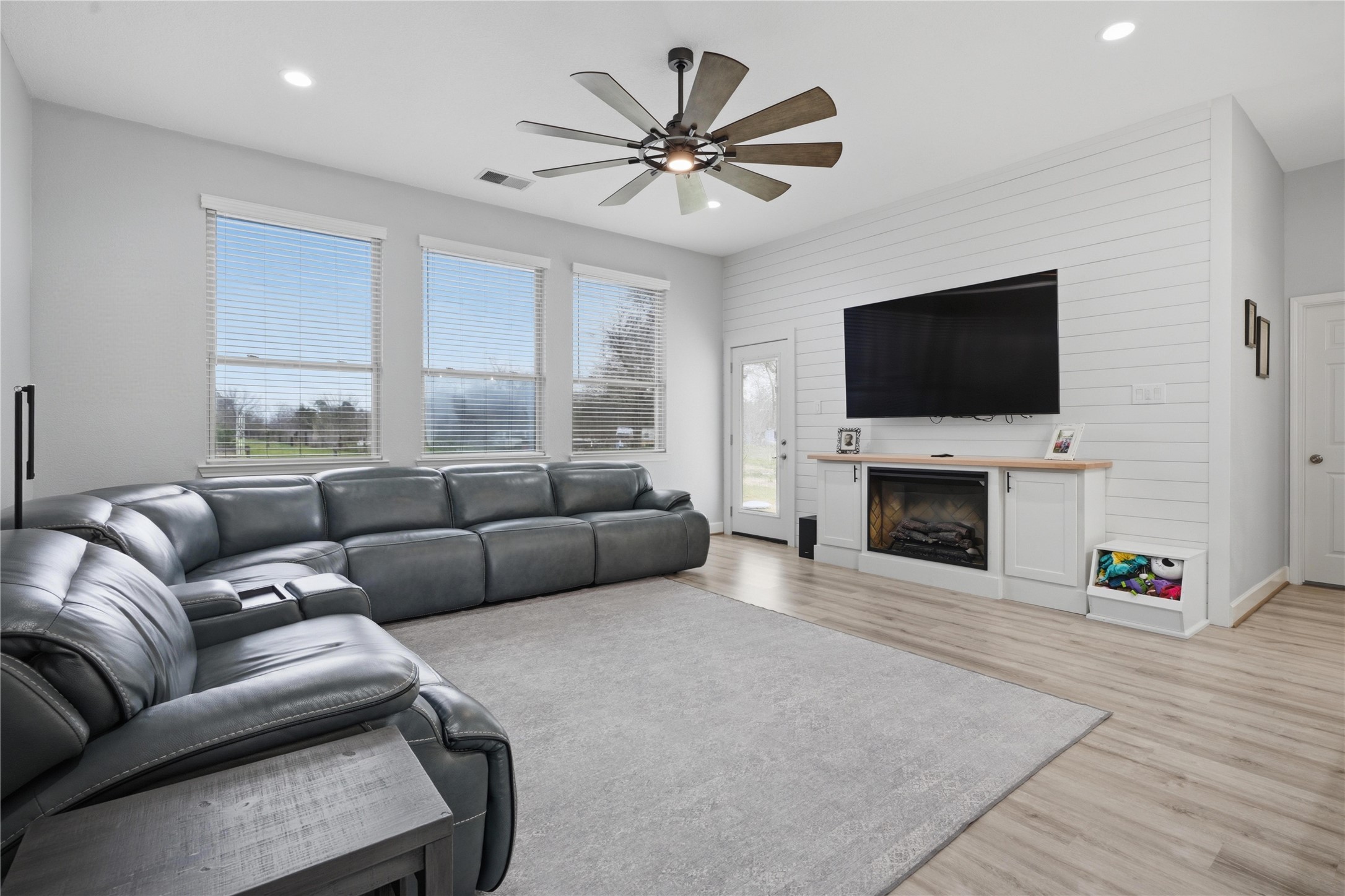 615 Lilley Road Alvin, TX 77511 - Photo 4 of 42 Living room upgrades include custom ship-lap wall, oversized ceiling fan, backdoor with internal blinds, and built-in electric fireplace with butcher block mantle.