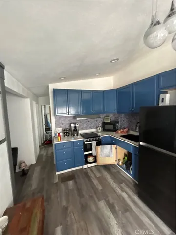 a kitchen with stainless steel appliances granite countertop a refrigerator a sink dishwasher a stove and white countertops with wooden floor