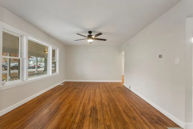 a view of an empty room with wooden floor and a window