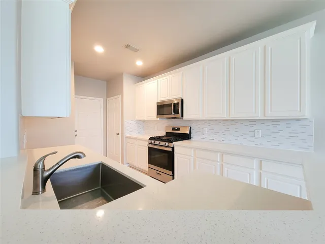 a kitchen with granite countertop a sink a stove a microwave and cabinets