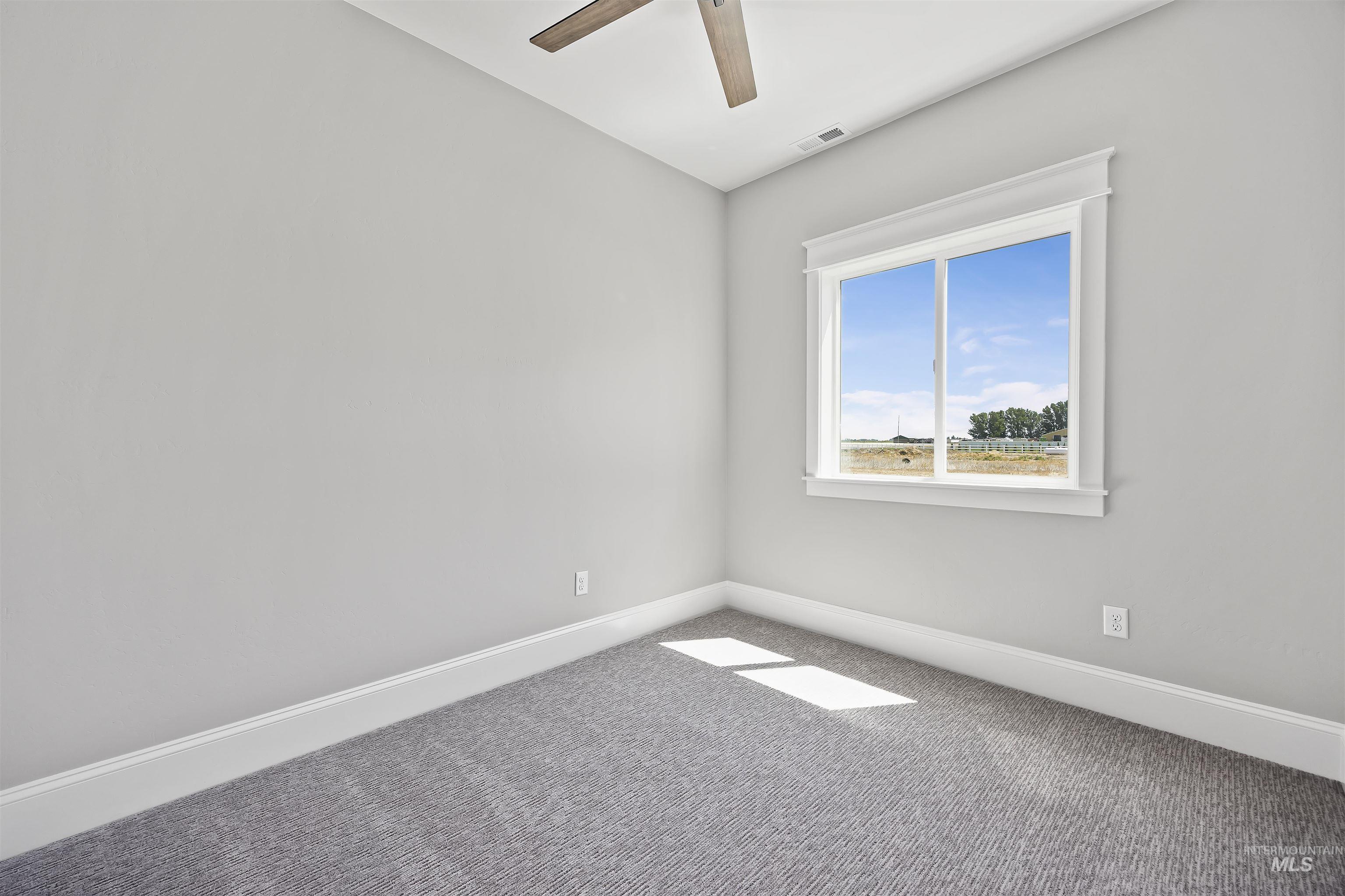 378 West 100 South Rupert, ID 83350 - Photo 34 of 50 Bright room featuring a large window with detailed trim, light gray walls, and textured gray carpeting