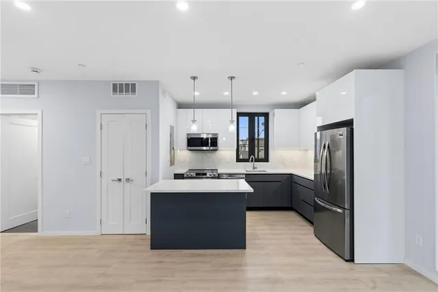 a kitchen with kitchen island a sink stainless steel appliances and window