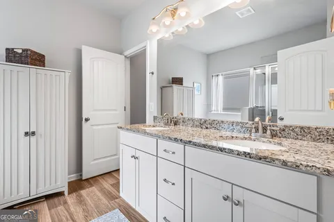 a bathroom with a granite countertop double vanity sink and mirror