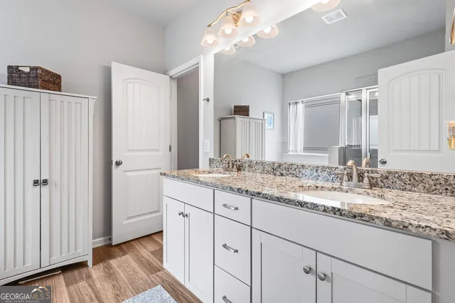 a bathroom with a granite countertop double vanity sink and mirror