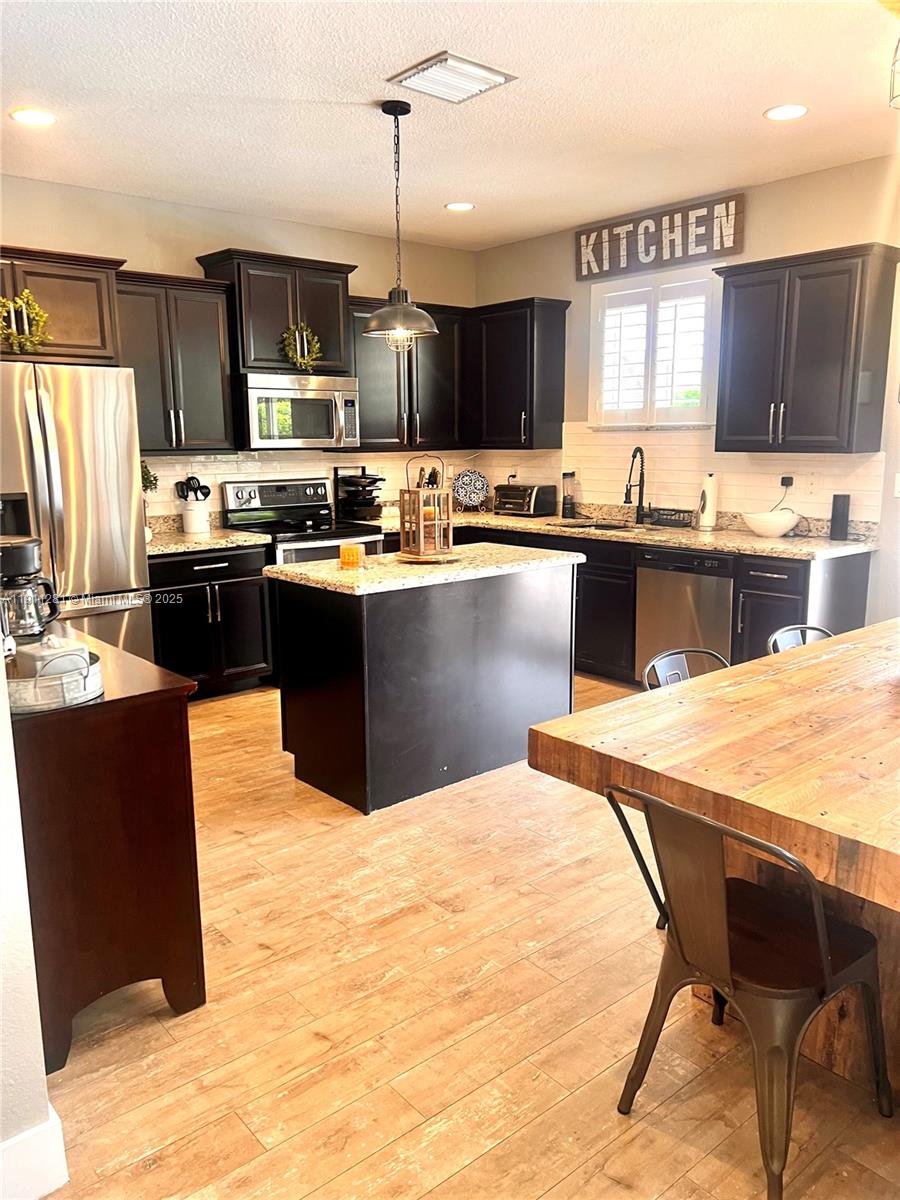 12780 Southwest 224th Street Miami, FL 33170 - Photo 4 of 29 a large kitchen with kitchen island a large counter top space appliances and cabinets