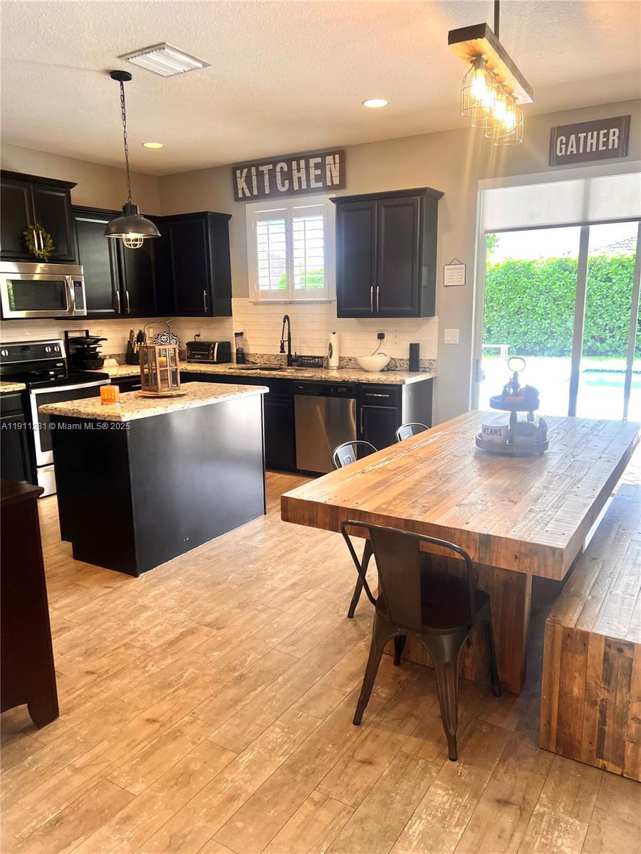 12780 Southwest 224th Street Miami, FL 33170 - Photo 5 of 29 a kitchen with stainless steel appliances kitchen island granite countertop a table chairs sink and microwave