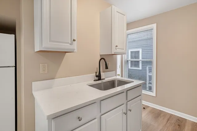 a kitchen with stainless steel appliances granite countertop a sink and a white cabinets with wooden floor