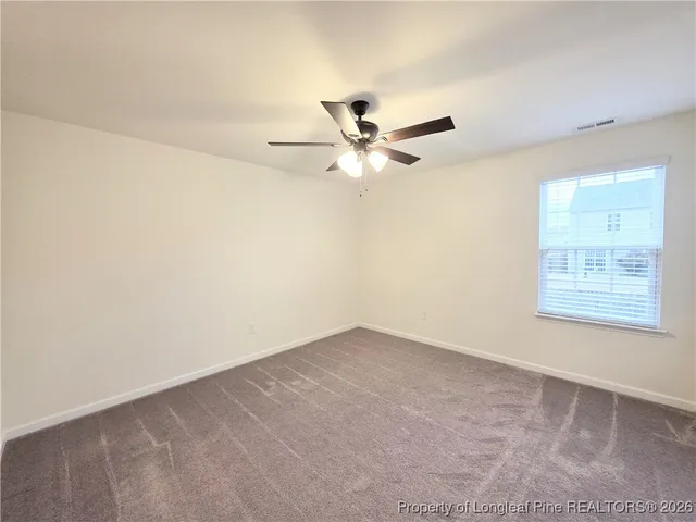 an empty room with a window and a fan