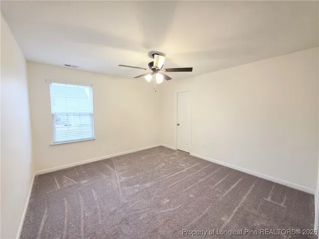 an empty room with fan and windows