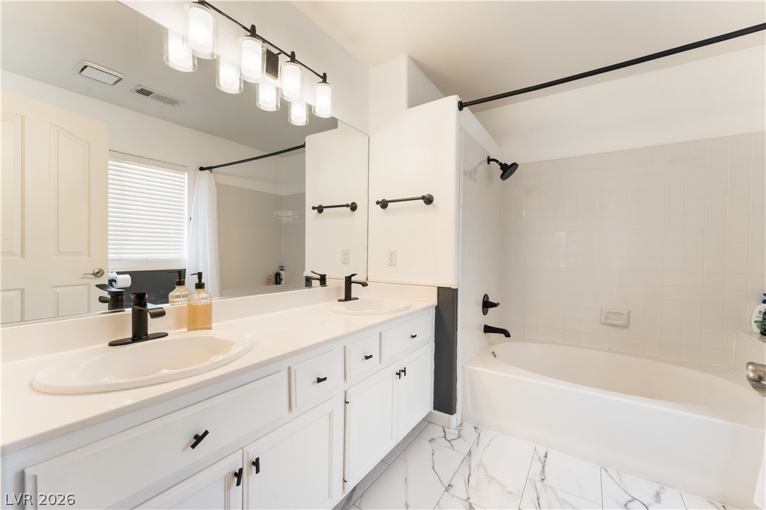 8872 Chapman Point Las Vegas, NV 89129 - Photo 16 of 29 Dual vanity with bright white cabinetry and modern fixtures, accompanied by a pristine soaking tub.
