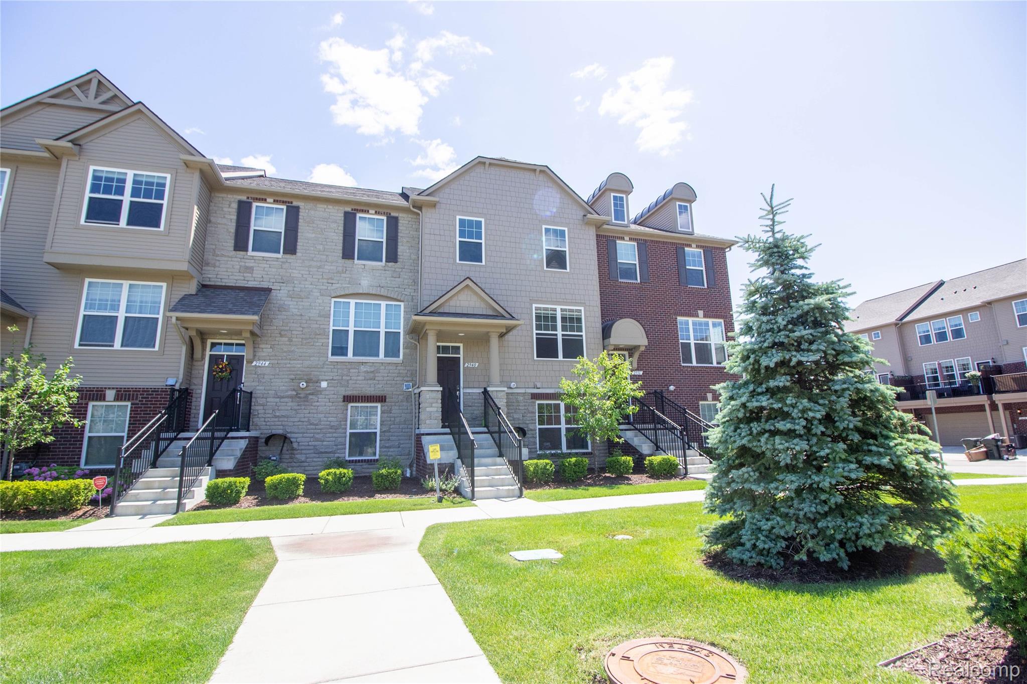 2940 Glenbar Circle Rochester, MI 48307 - Photo 2 of 15 Multi-level townhome featuring a stone and siding facade, black shutters, white window trim, and a covered entry