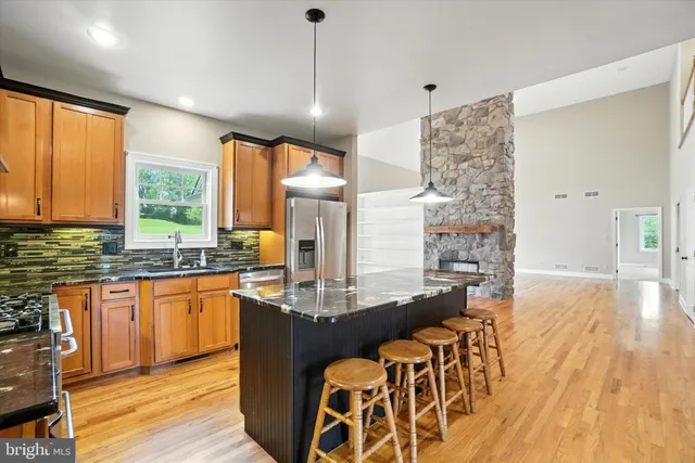 a kitchen with stainless steel appliances granite countertop a refrigerator a stove top oven a sink dishwasher and wooden cabinets with wooden floor