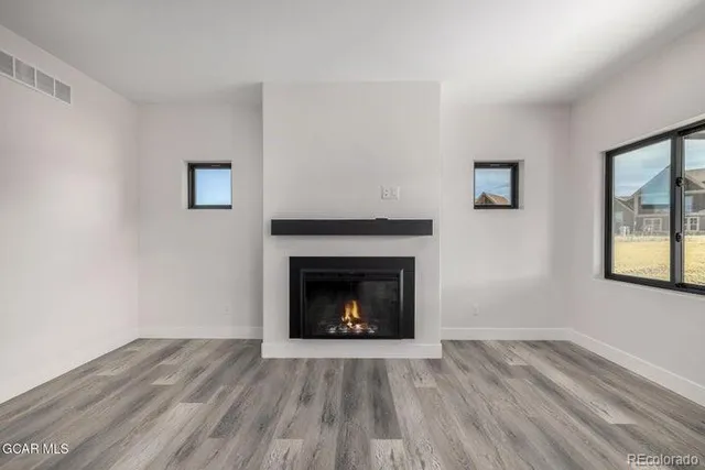 a view of an empty room with wooden floor and a fireplace