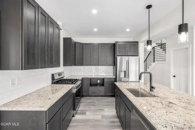 a kitchen with stainless steel appliances granite countertop a sink a oven and a fireplace with wooden floor
