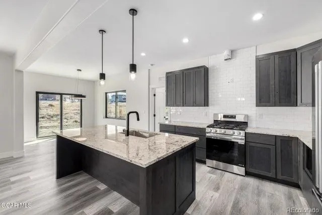 a kitchen with stainless steel appliances granite countertop a sink stove and refrigerator