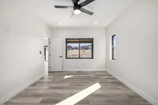 a view of a livingroom with a ceiling fan & wooden floor
