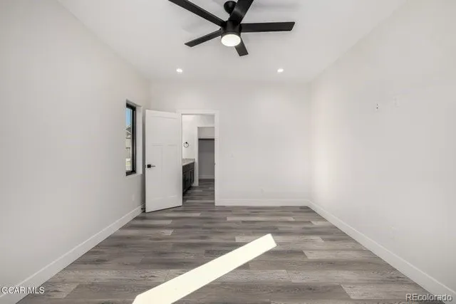 an empty room with wooden floor chandelier fan and windows
