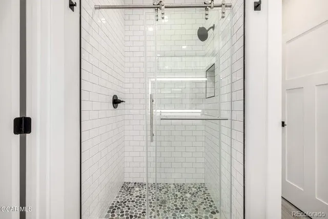 a bathroom with a double vanity sink a large mirror and shower