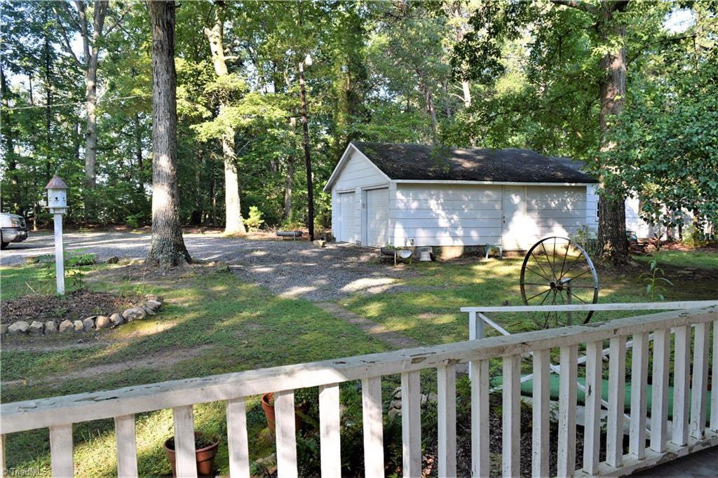 1030 Ellisboro Road Madison, NC 27025 - Photo 18 of 30 View from 8 ft wide wrap around porch. Looking out over detached 2 car garage/workshop and walkway to driveway. Beautiful mature hardwood trees surrounding house to provide great shade.