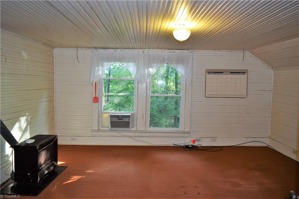 1030 Ellisboro Road Madison, NC 27025 - Photo 29 of 30 Large Room that could be used for Bedroom, if needed (no closet). Note gas heater and window unit. Beadboard wall & ceiling