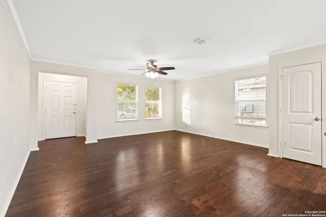 an empty room with wooden floor chandelier and windows