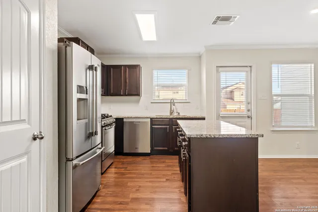 a kitchen with granite countertop a refrigerator stove top oven and sink