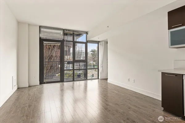 a view of an empty room with a window and wooden floor
