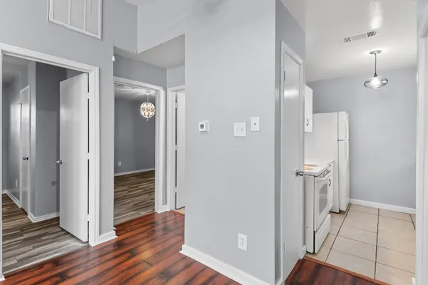 a view of a hallway with wooden floor and a bathroom