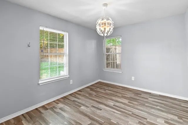 a view of an empty room with window and wooden floor