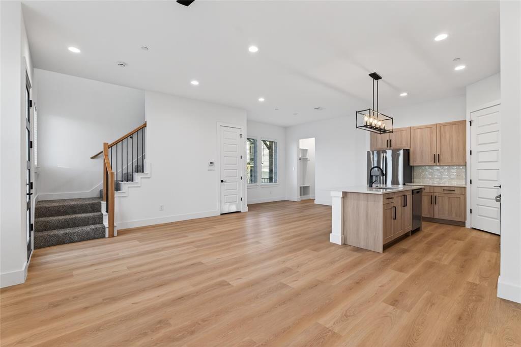 8901 Lowell Street Rowlett, TX 75089 - Photo 24 of 24 Kitchen with open floor plan, a kitchen island with sink, light wood finish cabinets, light wood-style floors, and stainless steel appliances