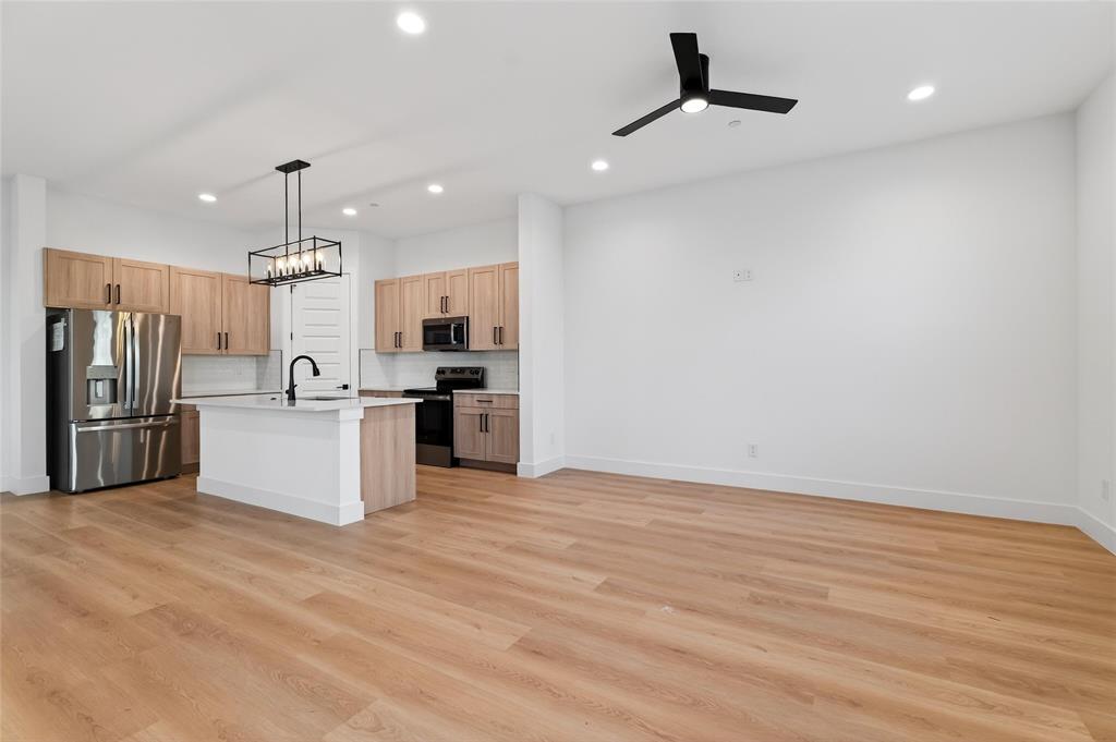 8901 Lowell Street Rowlett, TX 75089 - Photo 6 of 24 Kitchen featuring stainless steel appliances, a ceiling fan, a center island with sink, decorative backsplash, and light wood finish cabinets