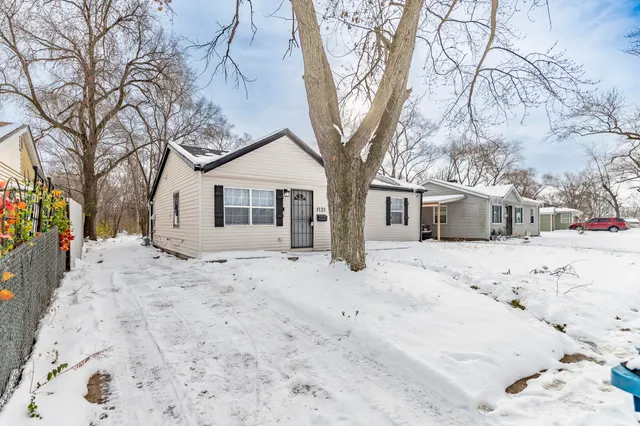 a tree covered with snow in front of house
