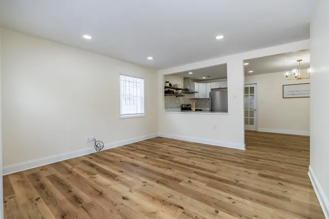 a view of empty room with wooden floor and window