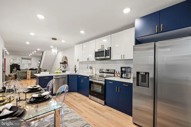 a kitchen with stainless steel appliances kitchen island granite countertop a refrigerator a sink dishwasher a stove and a dining table with wooden floor