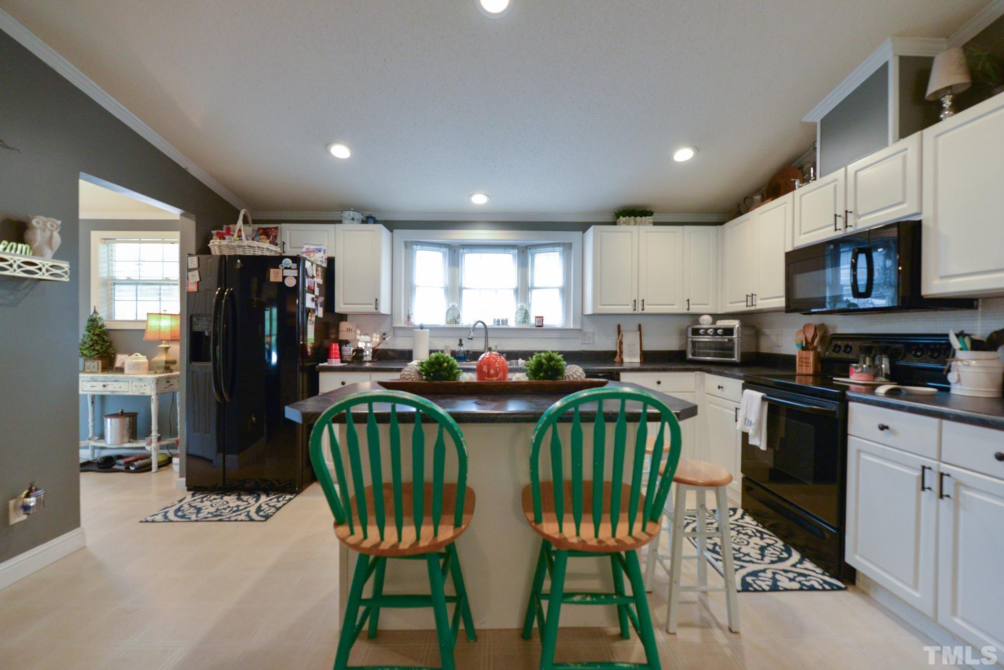 7175 Driver Road Zebulon, NC 27597 - Photo 8 of 30 a kitchen with stainless steel appliances kitchen island granite countertop a refrigerator a stove a sink a dining table and chairs